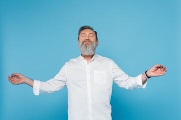 bearded master guru with closed eyes showing gyan mudra while meditating isolated on blue.