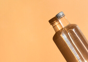 Transparent plastic bottle of water close up top view on the sunny orange background. Copy space
