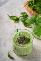Spinach smoothie healthy green. Vegan smoothie or milkshake from spinach, banana and chia seeds on gray concrete table background. Clean eating, alkaline diet. Top view. Mock up.