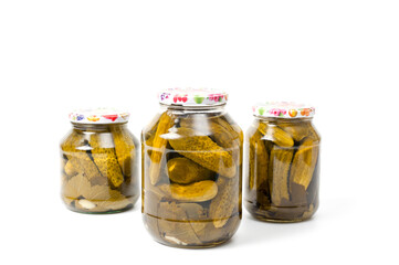 Fresh canned cucumbers in three jars, hermetically sealed with metal lids.