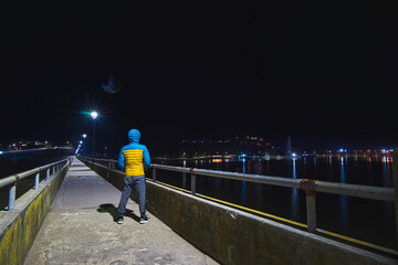 Person contemplating the landscape and the city at night standing alone on a bridge