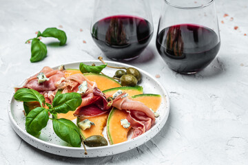 italian food with red wine, melon and prosciutto, Cantaloupe melon with prosciutto or jamon and...