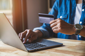 Fototapeta premium businesswoman hands holding credit card, typing on the keyboard of laptop, online shopping detail close up