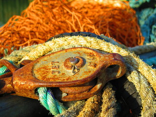 Yellow, rusty and blue mooring lines. Fishing nets, fishing industry, old rope and rusty metal Pulley system part on fishing boat.