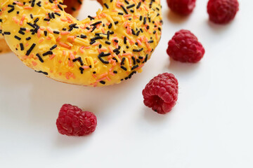 sweet dessert. round donuts with yellow icing isolated on white background and raspberries
