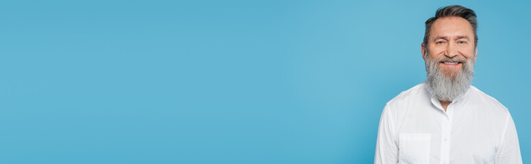 Fototapeta premium bearded guru man in white shirt smiling at camera isolated on blue, banner.