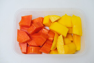 Fresh cut papaya and mango fruit inside plastic container