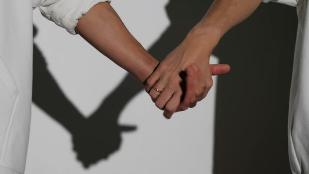 Female hands join in a handshake, close-up, white background.On one hand is an engagement ring