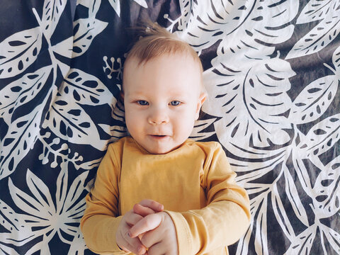 Adorable and cute 12 month or one year old baby boy portrait. Smiling and laughing toddler lying on the bed.