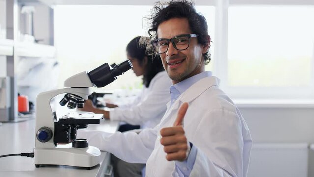 science research, work and people concept - male scientist with microscope working in laboratory