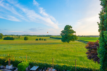Fields and trees in a green hilly grassy landscape under a blue sky at sunset in spring, Voeren,...