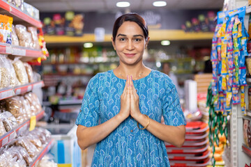 Portrait of an Indian woman greeting Namaste at grocery aisle of supermarket