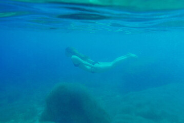 Fototapeta na wymiar Beautiful woman swimming underwater on paradise beach freedom wellbeing lifestyle summer vacation wanderlust