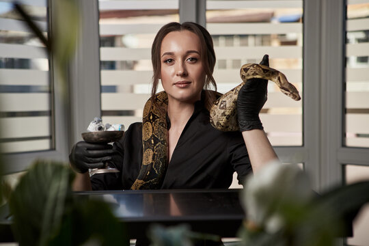 Portrait of beautiful female doctor cosmetologist with snake in the modern clinic. Symbol of medicine