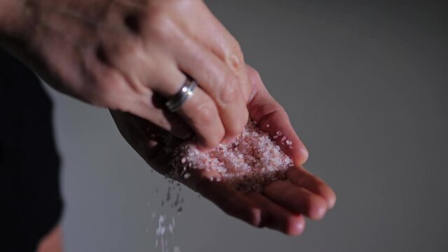 Women's palms pour sea salt close-up.Slow motion.