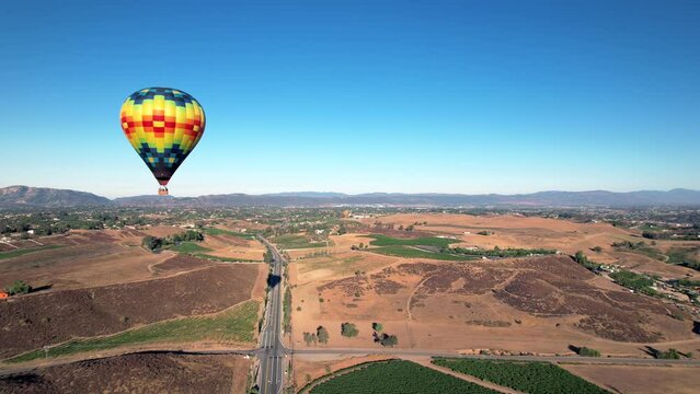 Flying by a hot air balloon floating over the Temecula vineyards in Southern California, aerial