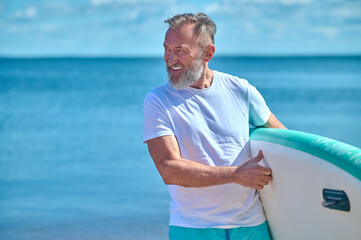 Man with surf boat looking away on seashore