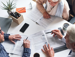 A mature couple meeting with a financial advisor to discuss retirement plans from above. A senior...