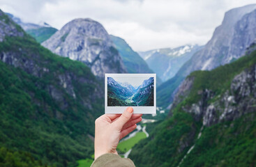 Hand holding up polaroid instant photo of travel destination glacial valley wanderlust inpiration...