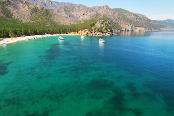 Beautiful seascape. Yachts near the shore and in the bay, tourists sunbathe on the sandy beach 