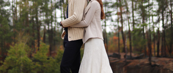 Wedding. Wedding outdoors in the forest. Young couple in love, the groom hugs the bride in a wedding dress. Standing on the rocks near the wedding ceremony. 