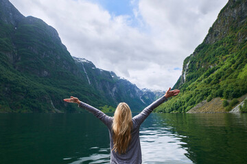 Travel adventure woman celebrates arms raised at view of majestic glacial valley fjord lake on...