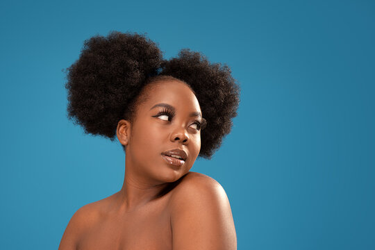 Beauty portrait of african young woman with clean healthy skin looking away, posing on blue studio background. Curly black hair.