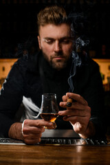 attractive barkeeper holds a glass of alcoholic drink and smoking cigar