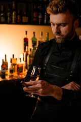 bartender holding a wine glass with an alcoholic drink and cuban cigar in his hand