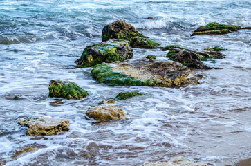 Turquoise shallow water surface and rocks stones on sea floor.
