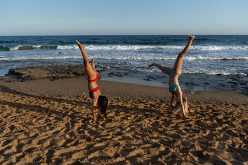 two girls in bikini spending a day on the beach at sunset