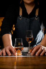 two beautiful glasses with drink on bar and hands of bartender nearby