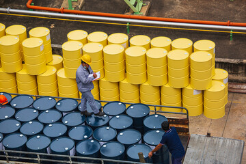 Male worker inspection record drum oil stock barrels yellow vertical or chemical for transportation...