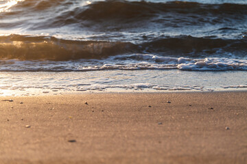 Beautiful sunset reflection on a waves on the beach. High-quality photo.
