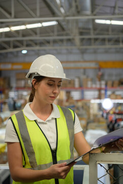 Female Warehouse Worker Counting Items In An Industrial Warehouse On The Factory's Mezzanine Floor. Which Is A Storage For Small And Light Electronic Parts.