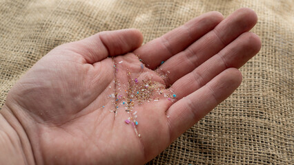 Close-up on micro plastic particles in a person hand. The concept for water pollution and global warming.  Macro shot on a bunch of microplastics that cannot be recycled