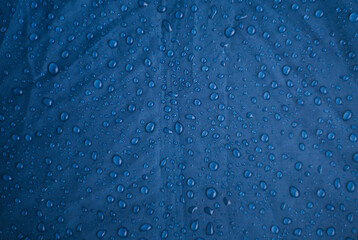 Rainwater drops on a blue background made of waterproof fabric. Texture and abstract background. - obrazy, fototapety, plakaty