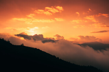 Beautiful sunset over the silhouette of the mountain with clouds. Dramatic sky cloudscape