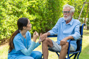Fototapeta premium Asian nurse takes care An elderly man sitting in a wheelchair holding hands to encourage him to take him out to relax in the garden at Nursing Home