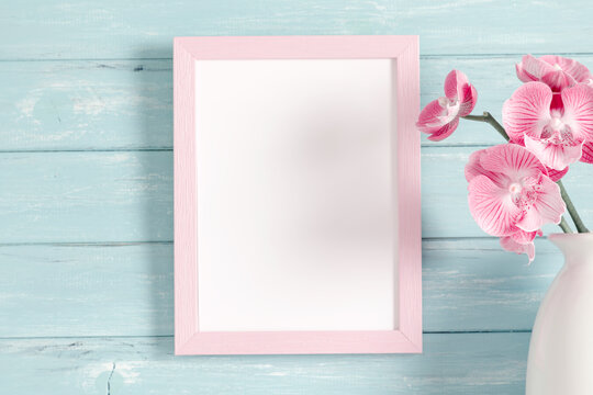 Beautiful flowers composition. Photo frame, gift pink, orchid flower on pastel light blue background. Valentines Day, Happy Women's Day. 