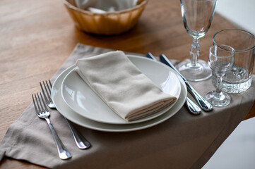 Festive romantic table setting with silverware, gray napkin and white crockery on beige silk...