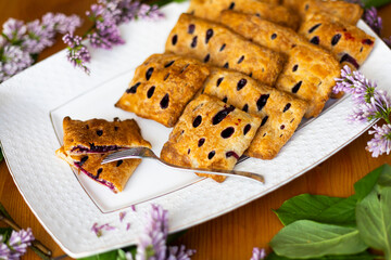 Puffs or puff pastry pies with holes with rhubarb and blueberries surrounded with lilac branches