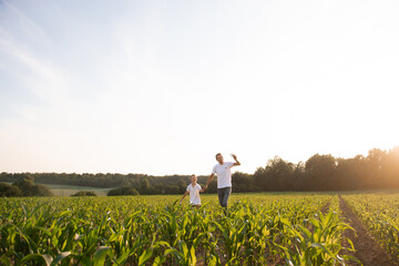 Cute boy in a cornfield with dad launching a plane