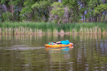 athletic, senior man is paddling a prone kayak on a lake in Colorado, this water sport combines aspects of kayaking and swimming