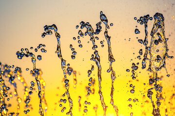 silhouettes of drops falling water fountain against the backdrop of the setting sun
