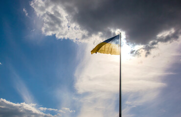 The national flag of the country of Ukraine against the background of the sun and blue sky. Patriotism and national symbol