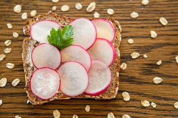 Scheibe Vollkornbrot mit Radieschen auf einem Rustikalen Holztisch