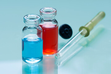Two medical bottles with potions and pipette on glass table.