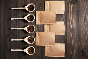 Different varieties of roasted natural coffee in wooden spoons and brown bags.