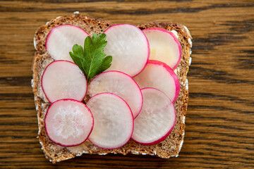 Scheibe Vollkornbrot mit Radieschen auf einem Rustikalen Holztisch